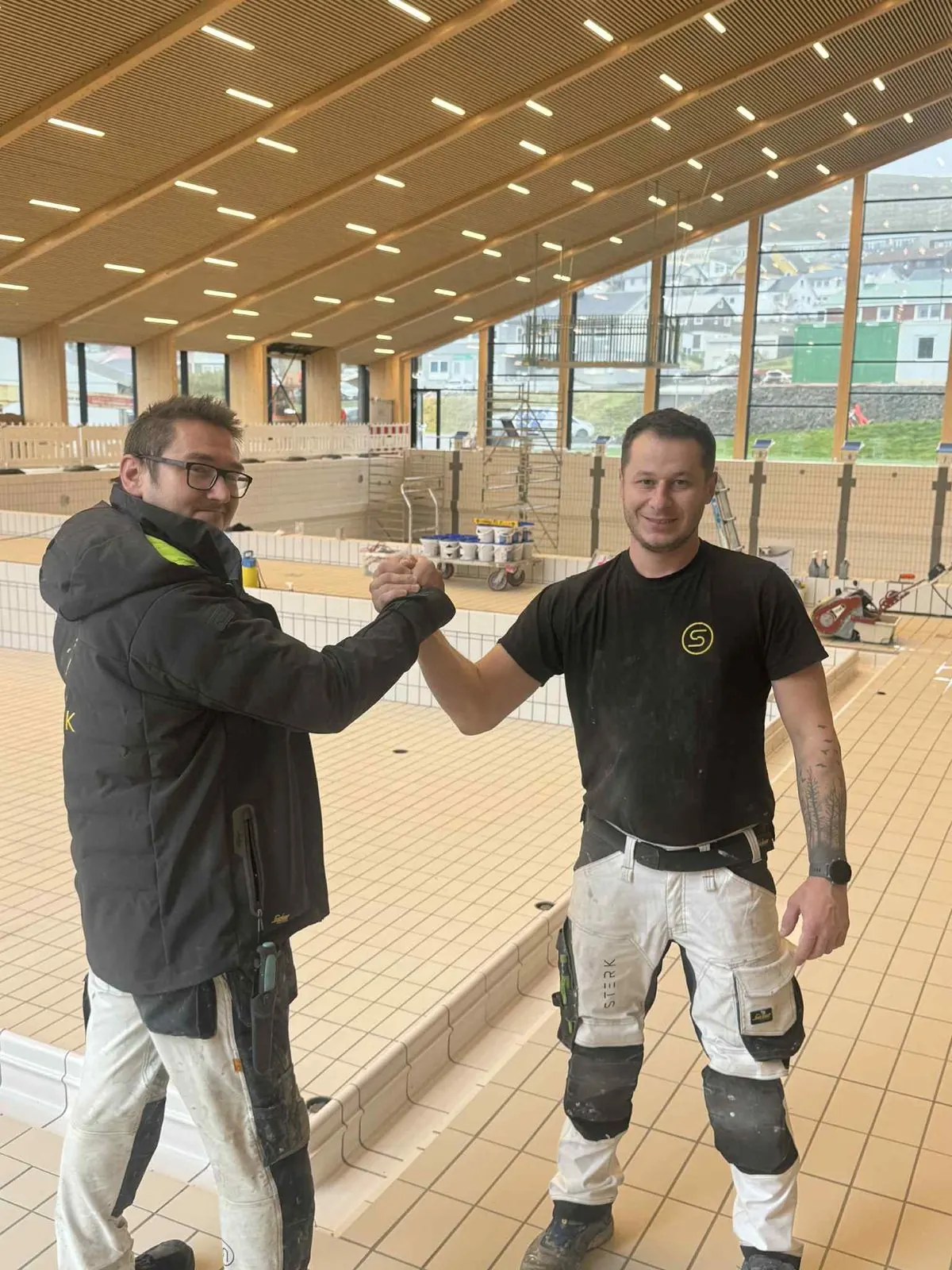 Two STERK crew members shaking hands inside the Bylgjan swimming hall