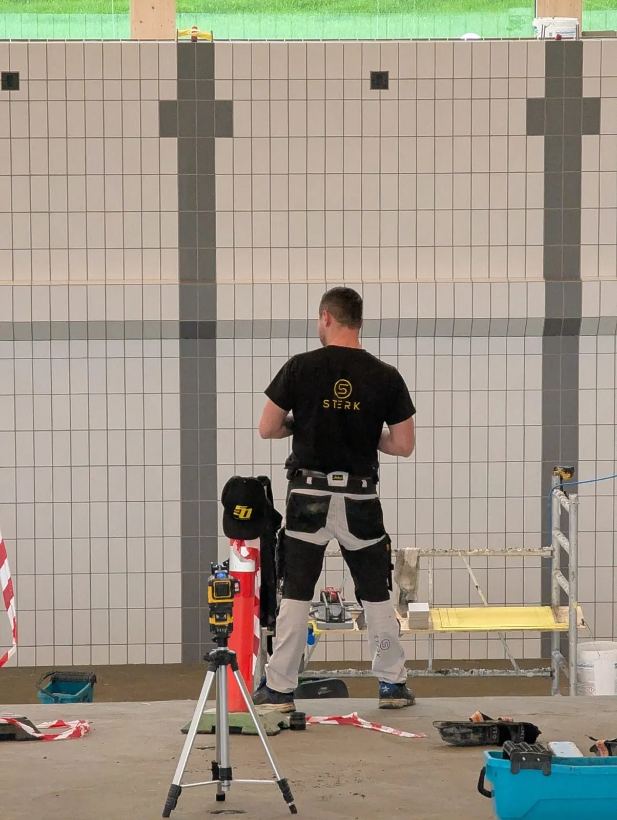 STERK worker in branded workwear tiling the pool